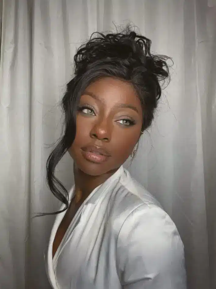 Woman with styled hair and white blouse in front of a soft gray curtain