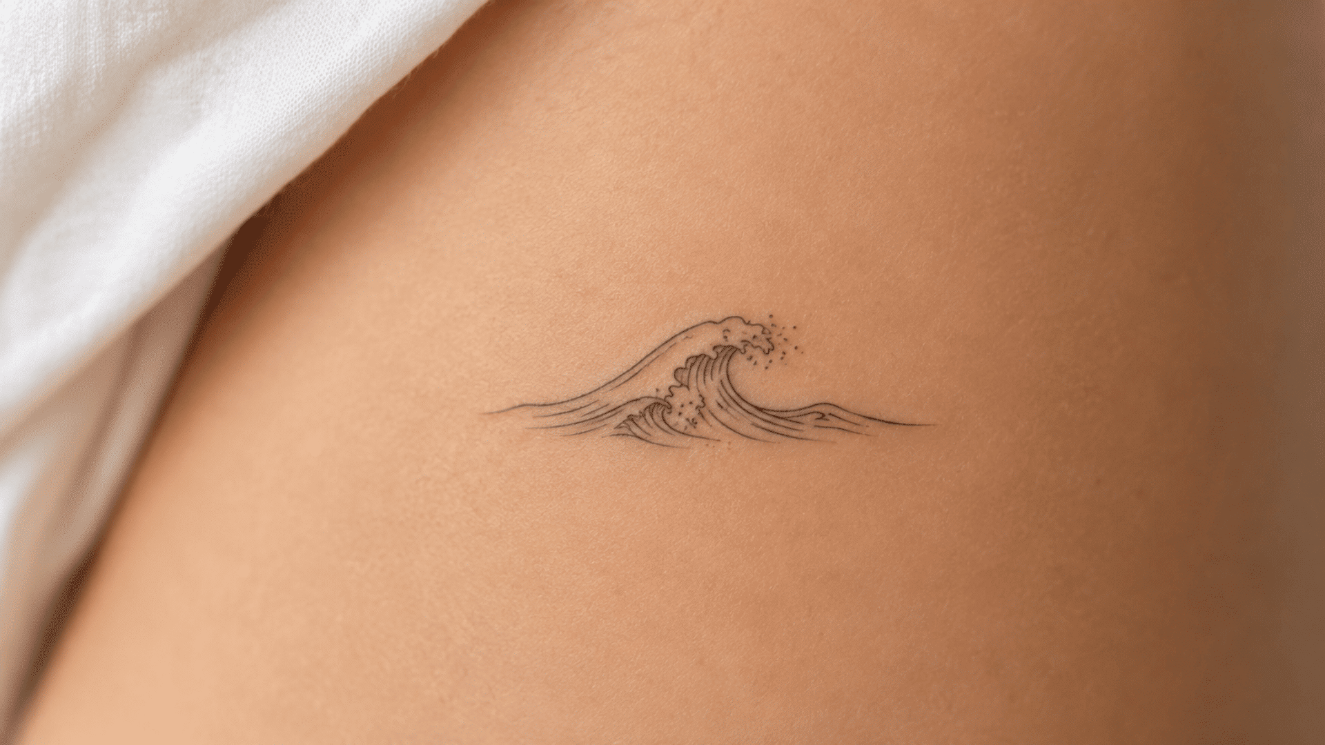minimalist fine-line wave tattoo with delicate black lines on the skin.