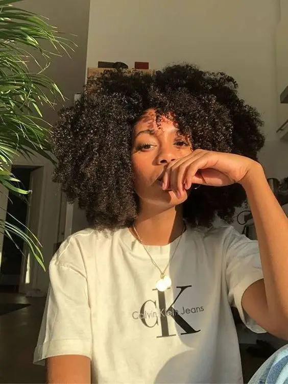 Person sitting indoors wearing a white Calvin Klein T-shirt with sunlight on face