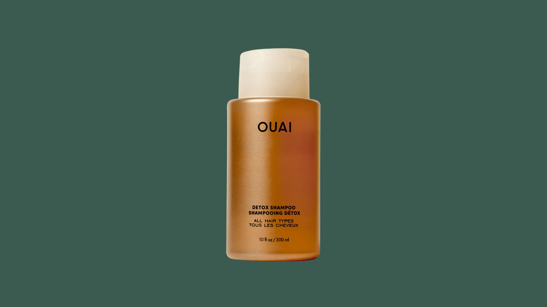 ouai detox shampoo bottle with amber packaging on a dark green background for hair care product display and beauty use