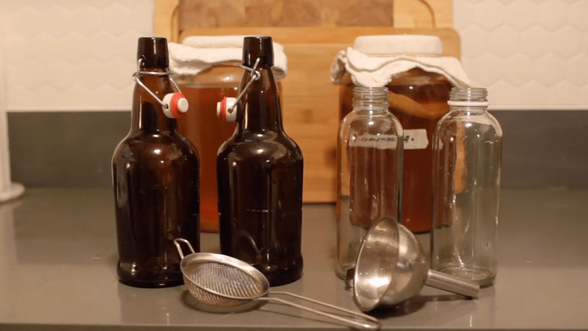 pouring finished kombucha into bottles and adding fresh fruit for flavor during second fermentation