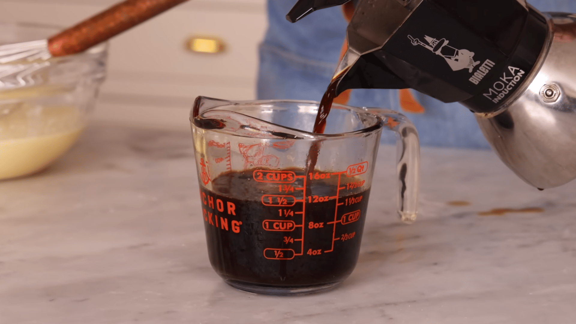 pouring hot coffee into the batter mixture to deepen the chocolate cocoa flavor