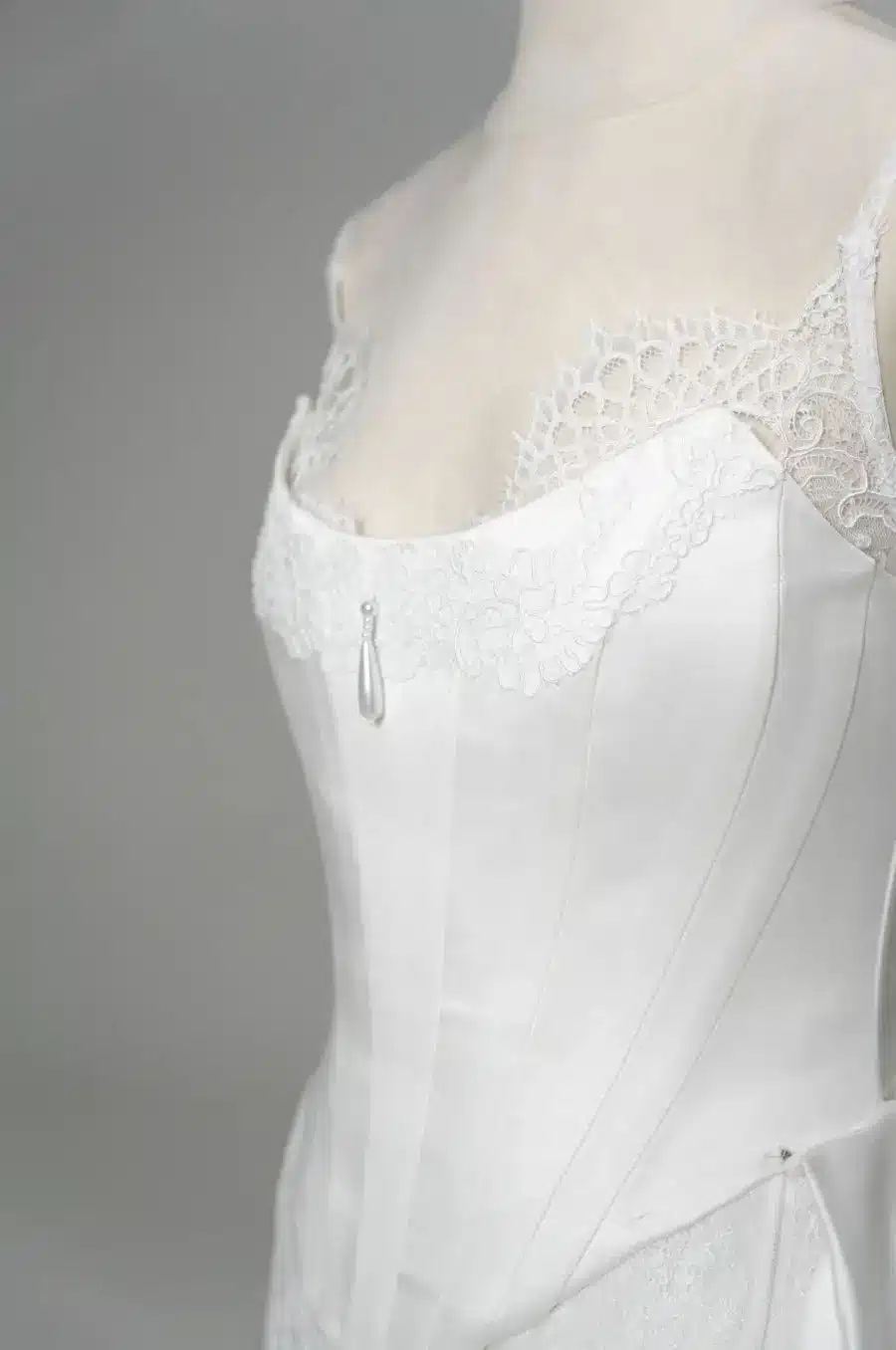 Close-up of white lace corset with intricate floral embroidery on mannequin in studio setting