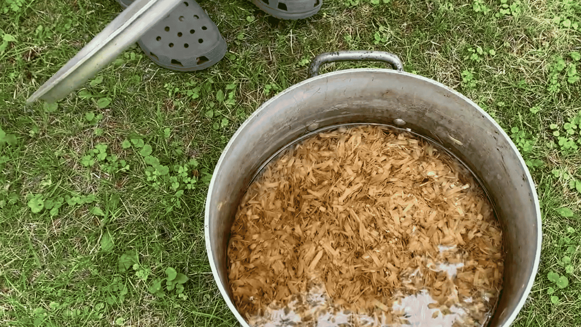 rehydrated aspen shavings soaking in water inside a large metal pot before excess water is drained