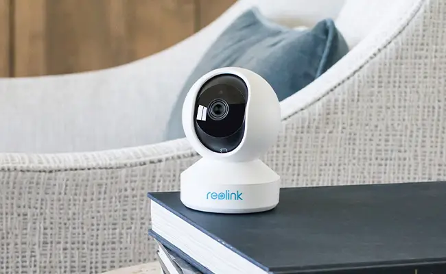 White security camera on stack of books in cozy living room setting