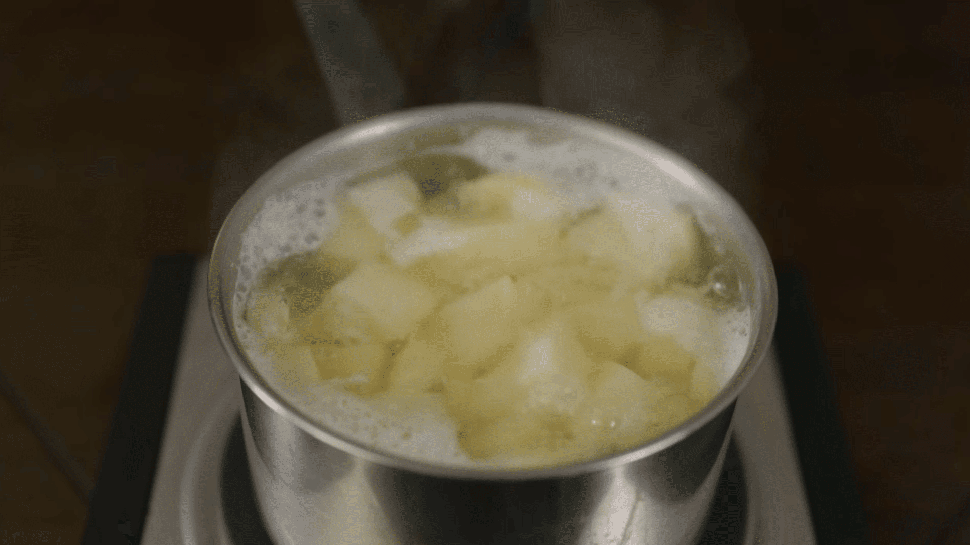 salt being added to a pot of potatoes and water before bringing everything to a boil