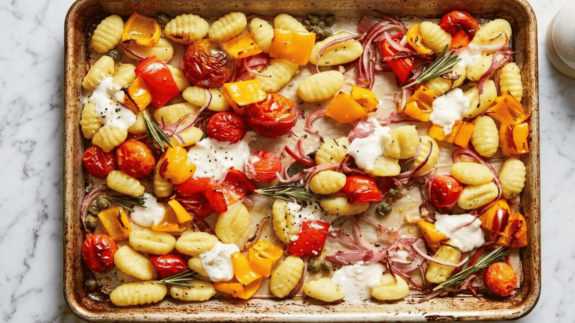 sheet pan gnocchi with roasted cherry tomatoes bell peppers red onion creamy cheese capers and rosemary