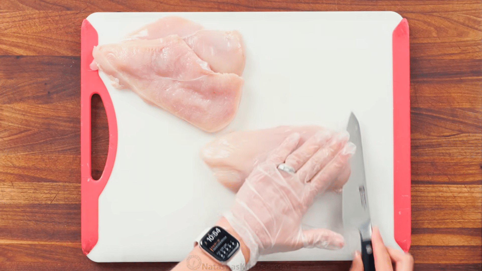 slicing chicken breasts lengthwise into thin chicken cutlets on a cutting board.