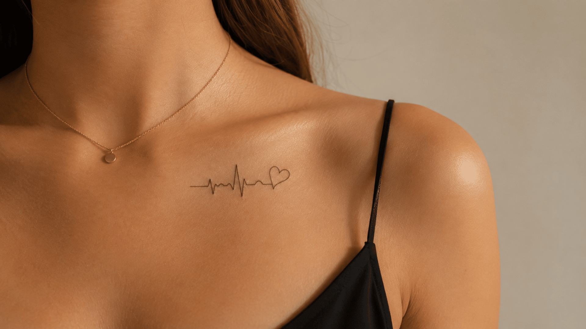 small heartbeat and heart tattoo on the collarbone with a black outfit.