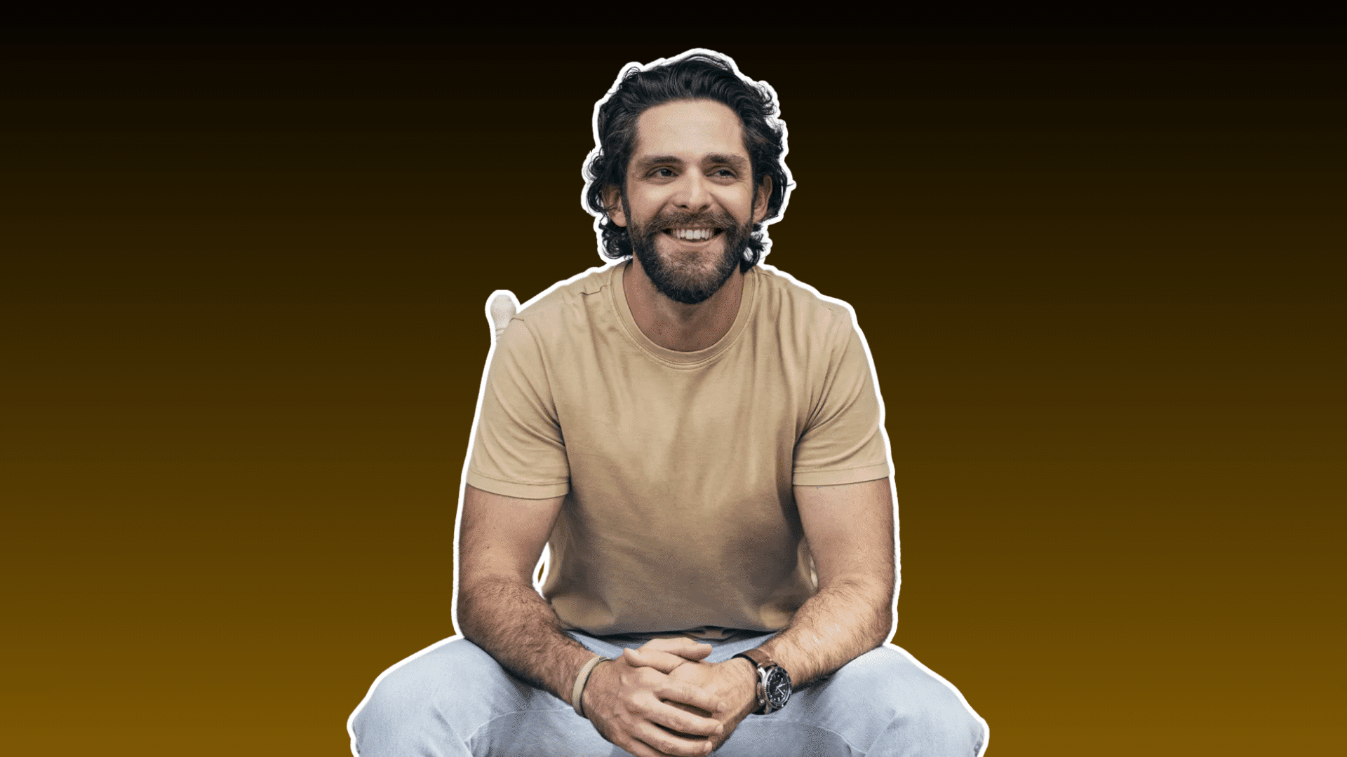 smiling bearded man with wavy hair wearing a beige shirt seated against a dark brown background