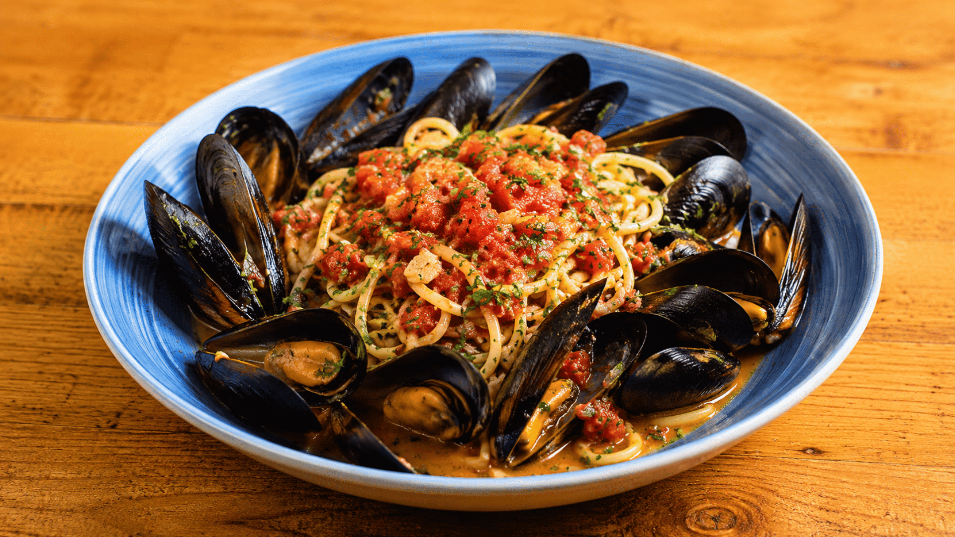 spaghetti with mussels tomato sauce garlic and herbs served in a blue bowl