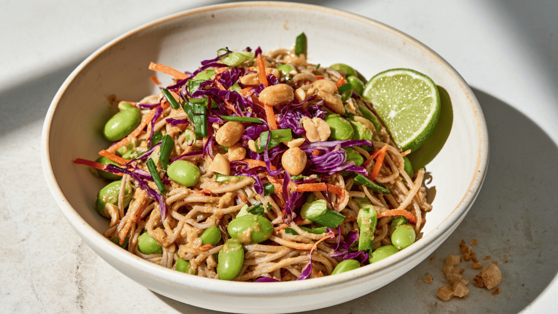 spicy peanut noodles with edamame red cabbage carrots green onions roasted peanuts and fresh lime