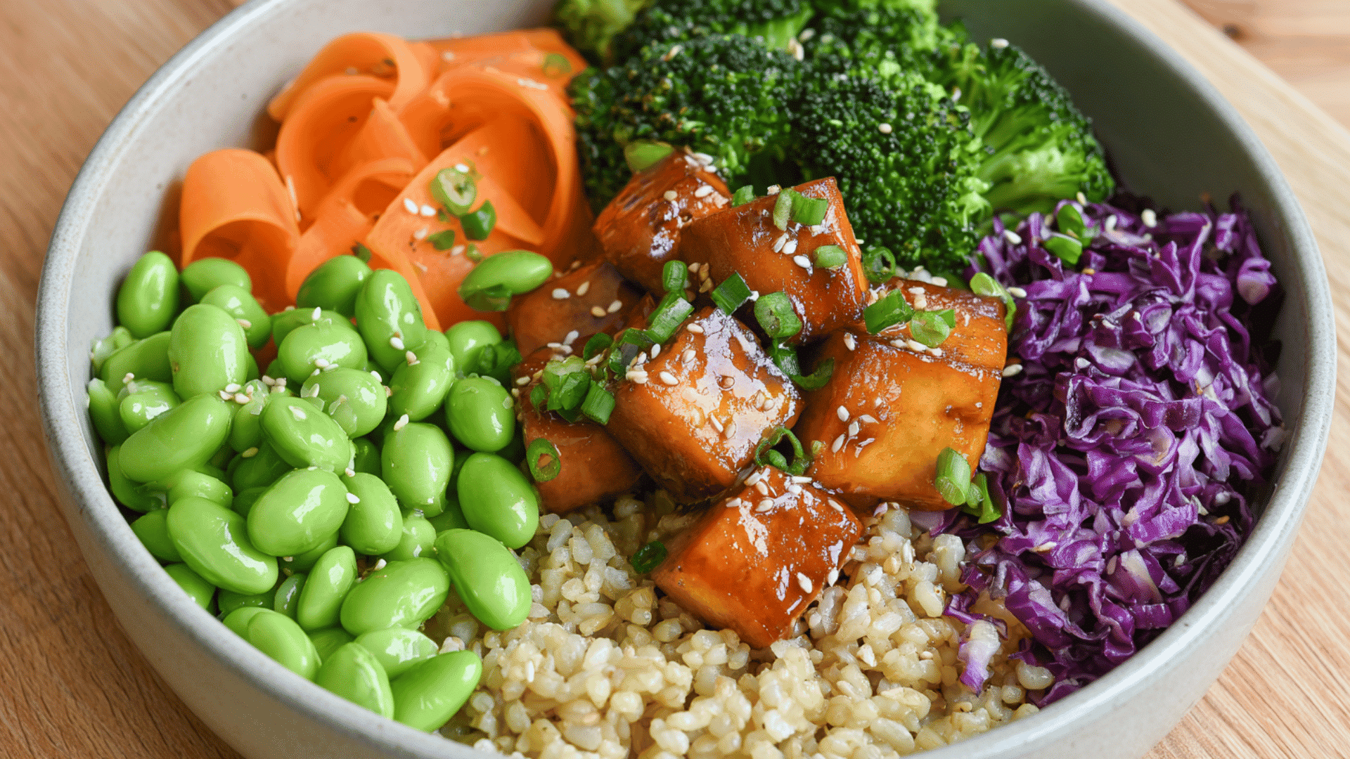 teriyaki tofu rice bowl with edamame broccoli carrots red cabbage green onions and sesame seeds