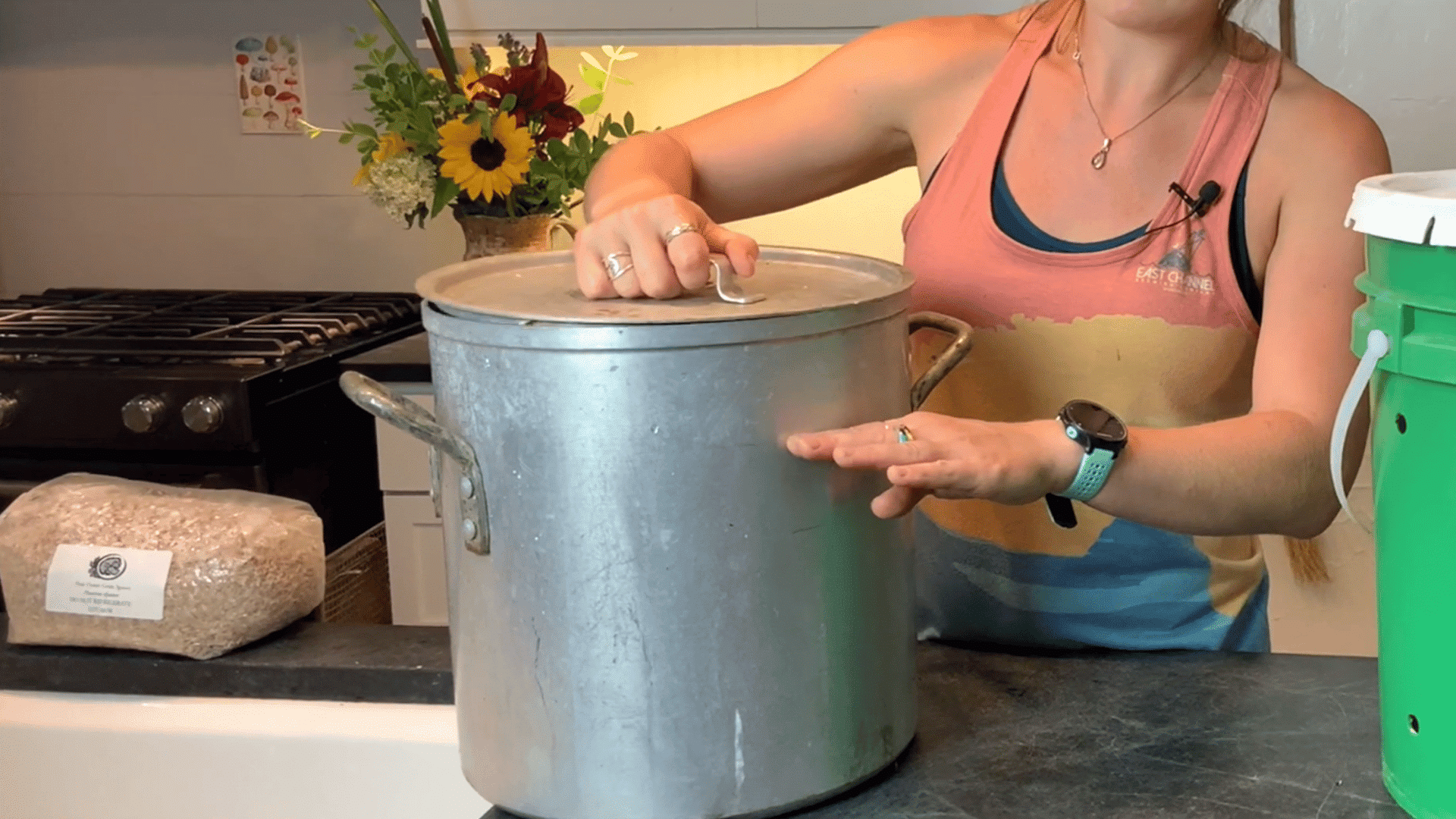 woman standing behind a covered metal pot used to boil water for hydrating measured aspen shavings