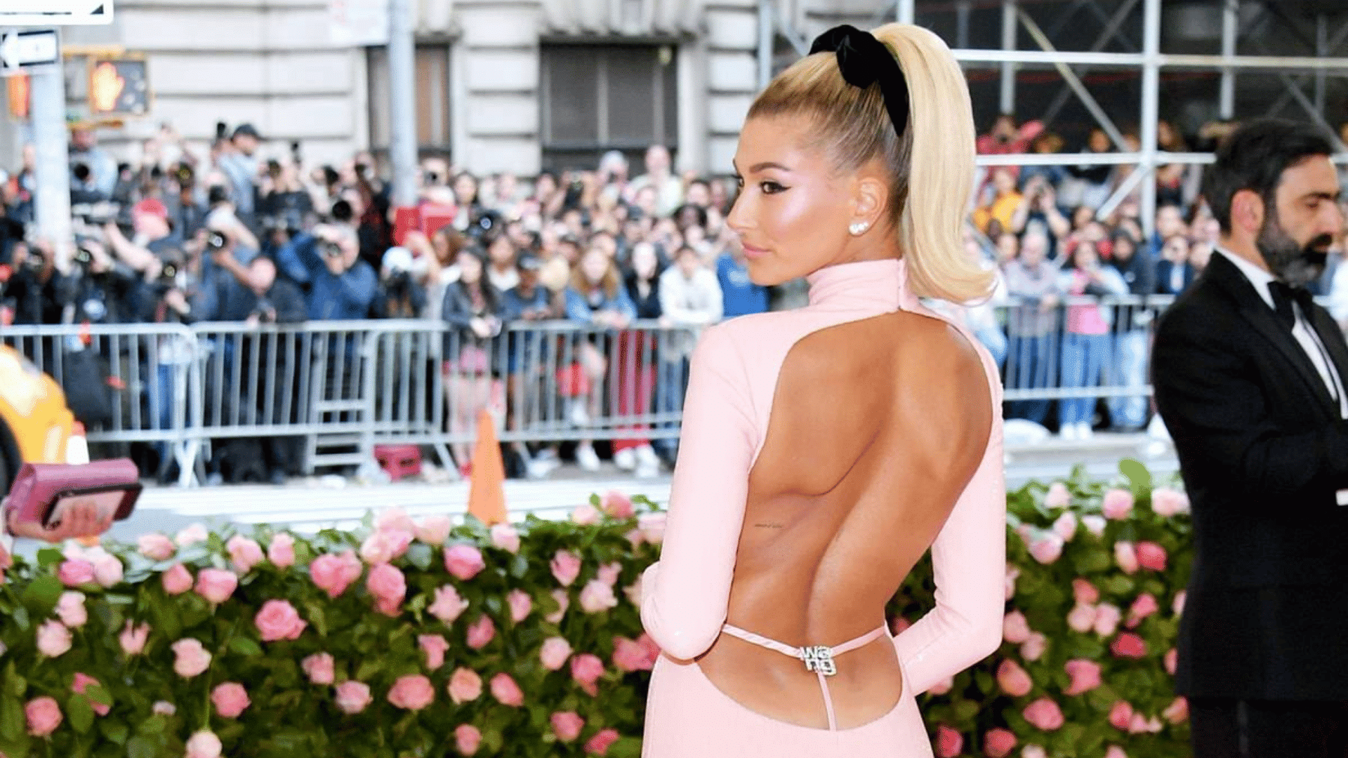 woman wearing a high slicked back ponytail with black bow pink backless dress and stud earrings at a formal event