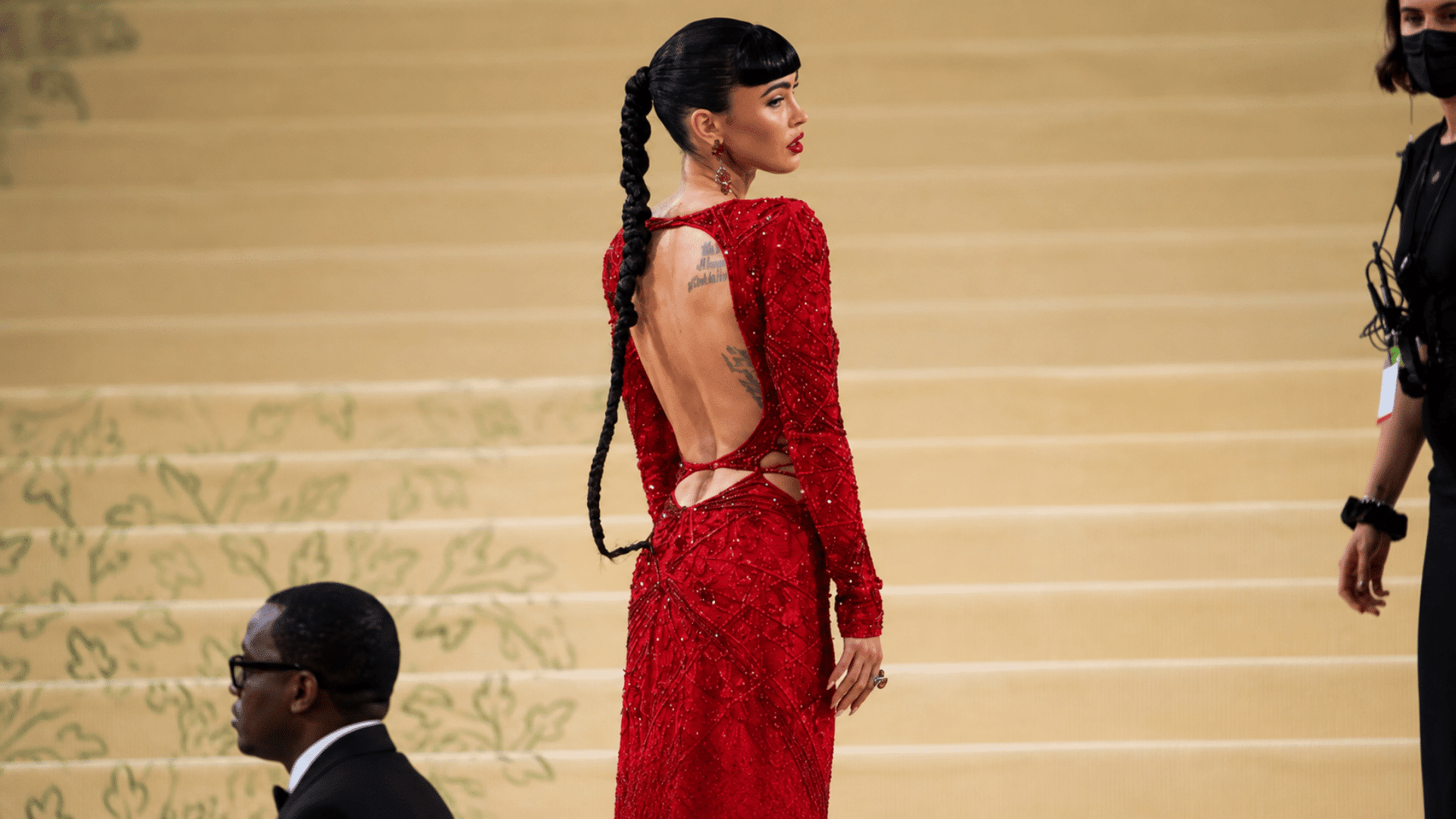 woman wearing a long braided ponytail with blunt bangs red embellished gown and statement earrings at a formal event
