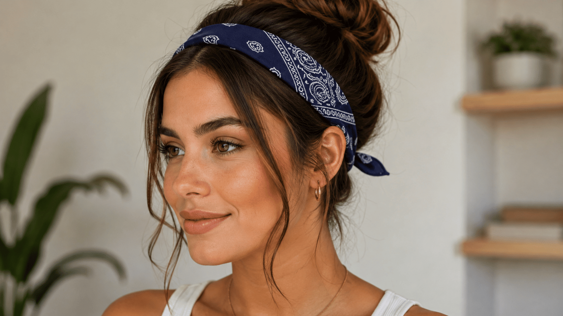 woman wearing a navy bandana as a classic headband, tied at the back with her hair styled in a loose bun.