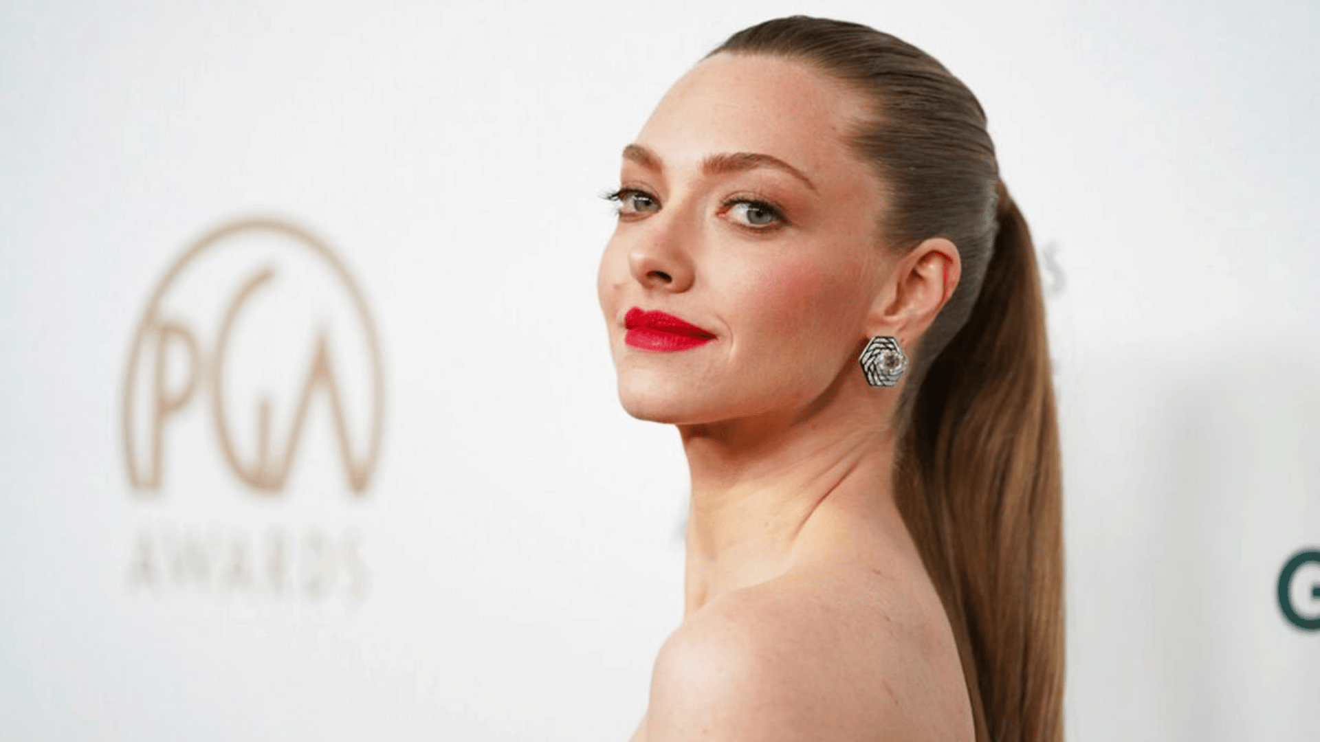 woman wearing a sleek high partless ponytail with straight brown hair bold red lipstick and statement earrings