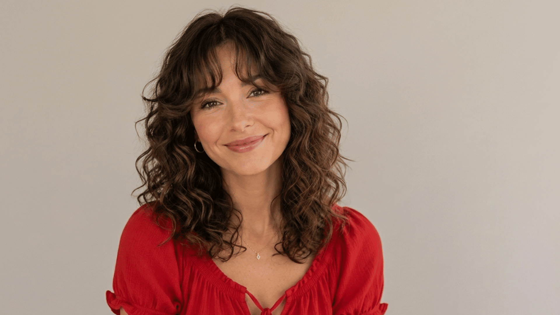 woman with a curly shag haircut soft curtain bangs defined layers and shoulder length brown curls