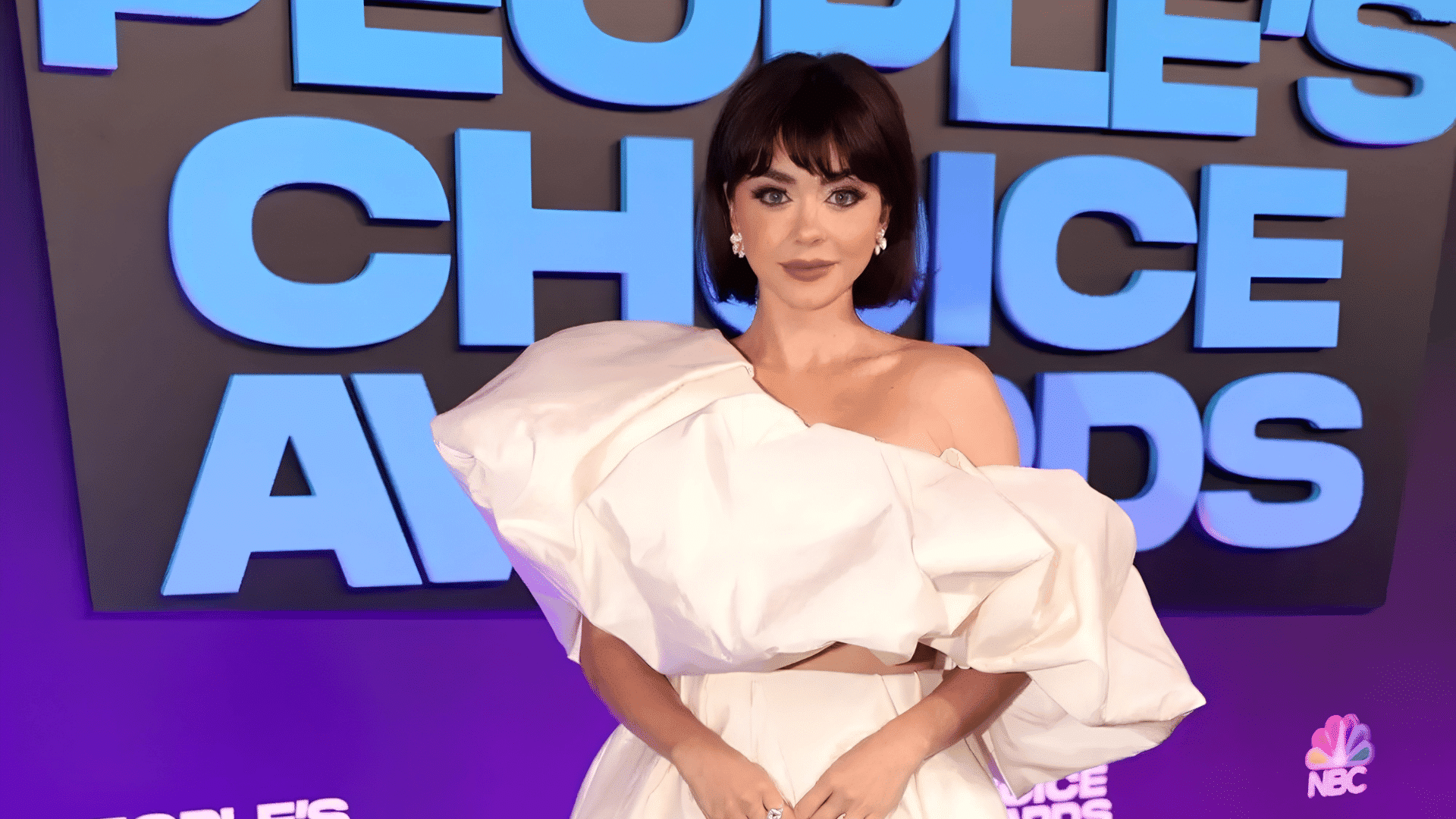woman with a layered bob with curtain bangs featuring sleek dark hair and soft fringe wearing a sculpted white gown