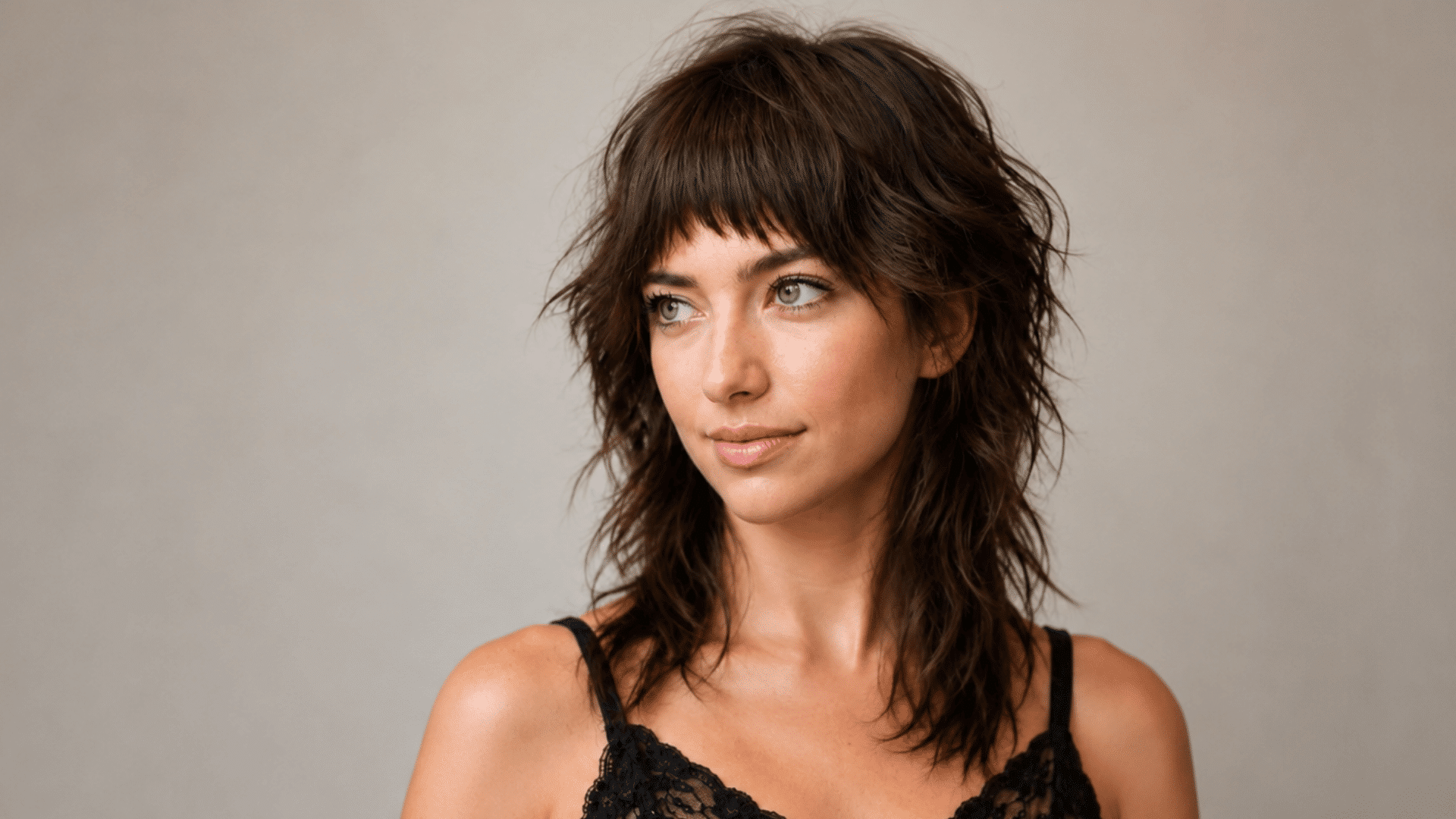 woman with a textured wolf haircut featuring choppy layers wispy bangs and tousled dark brown hair