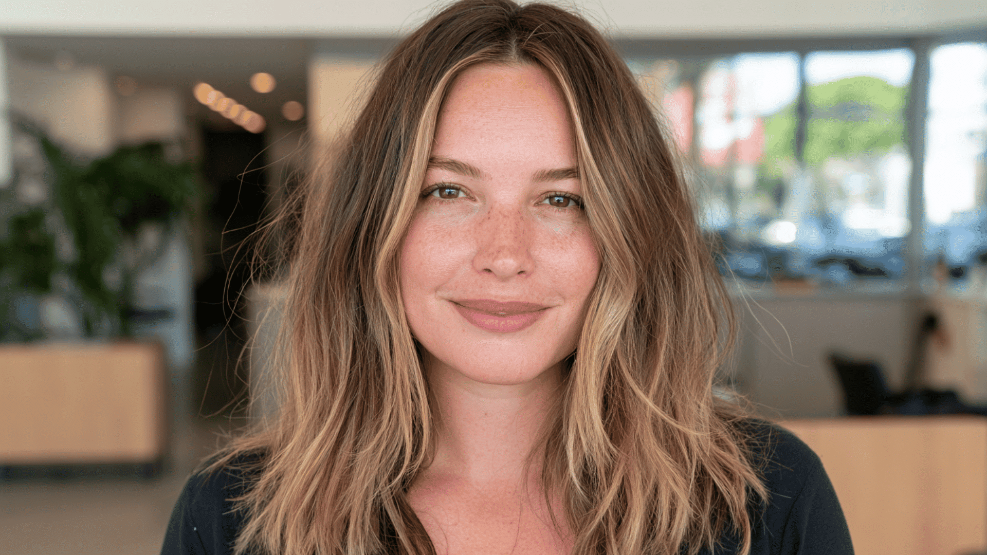 woman with beige blonde money piece highlights and soft roots on long wavy espresso brown hair