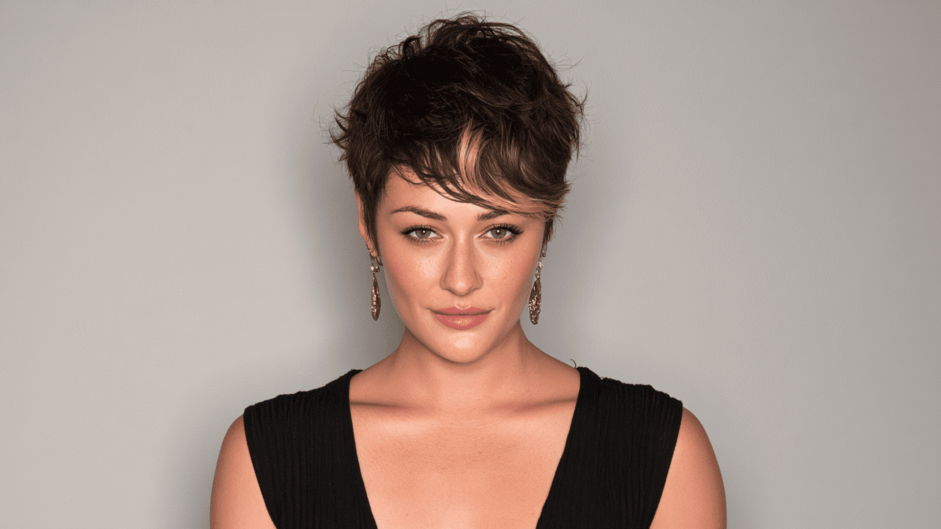 woman with caramel money piece highlights through the fringe of a textured brown pixie cut