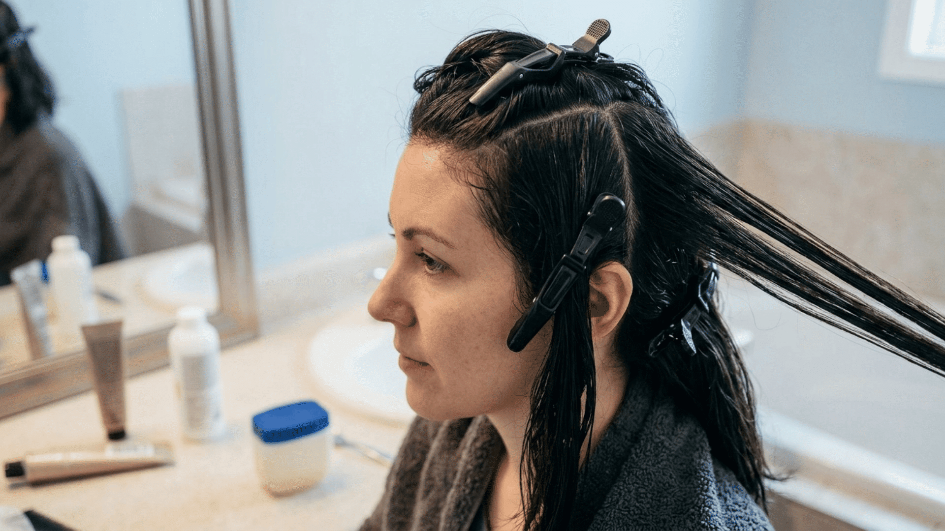 woman with dark hair divided into sections with clips while preparing for a highlighting treatment