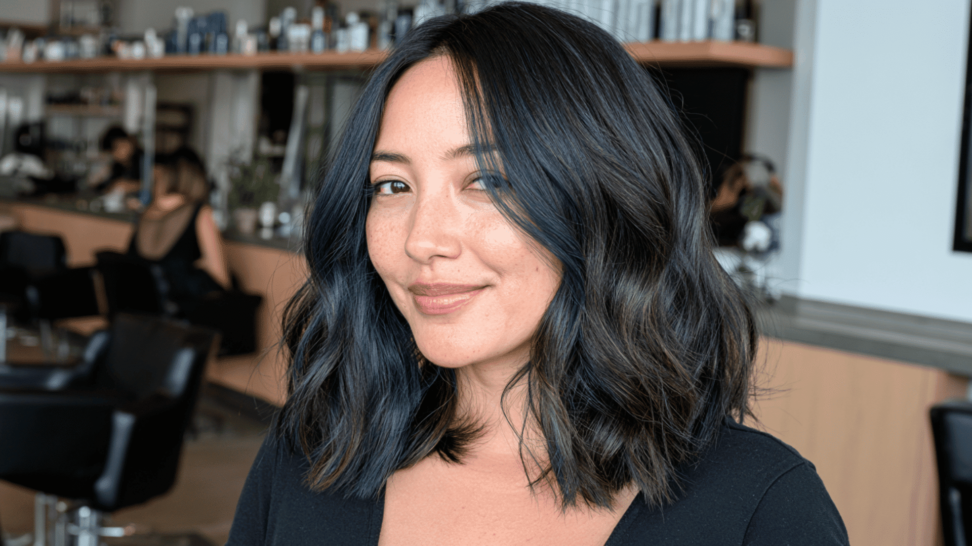 woman with deep blue money piece highlights framing glossy layered black hair in daylight