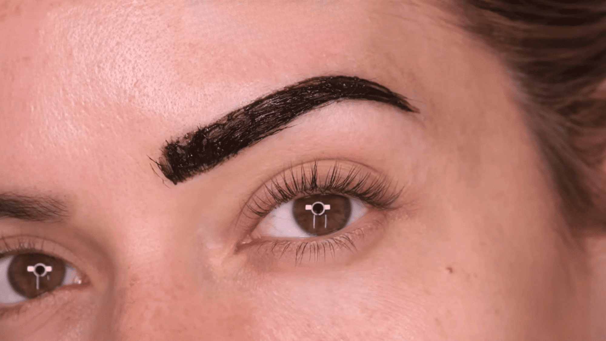 woman with freshly tinted eyebrows showing the darkened brow color during the processing stage