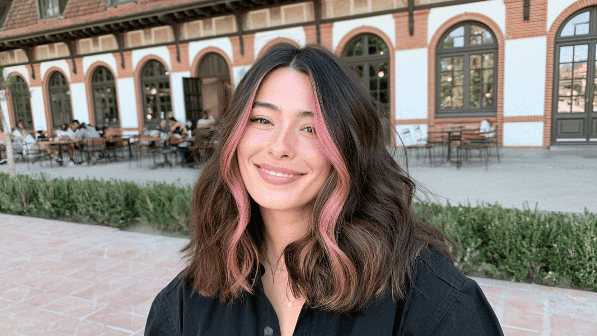 woman with soft pink money piece highlights framing shoulder length dark brown hair outdoors in daylight