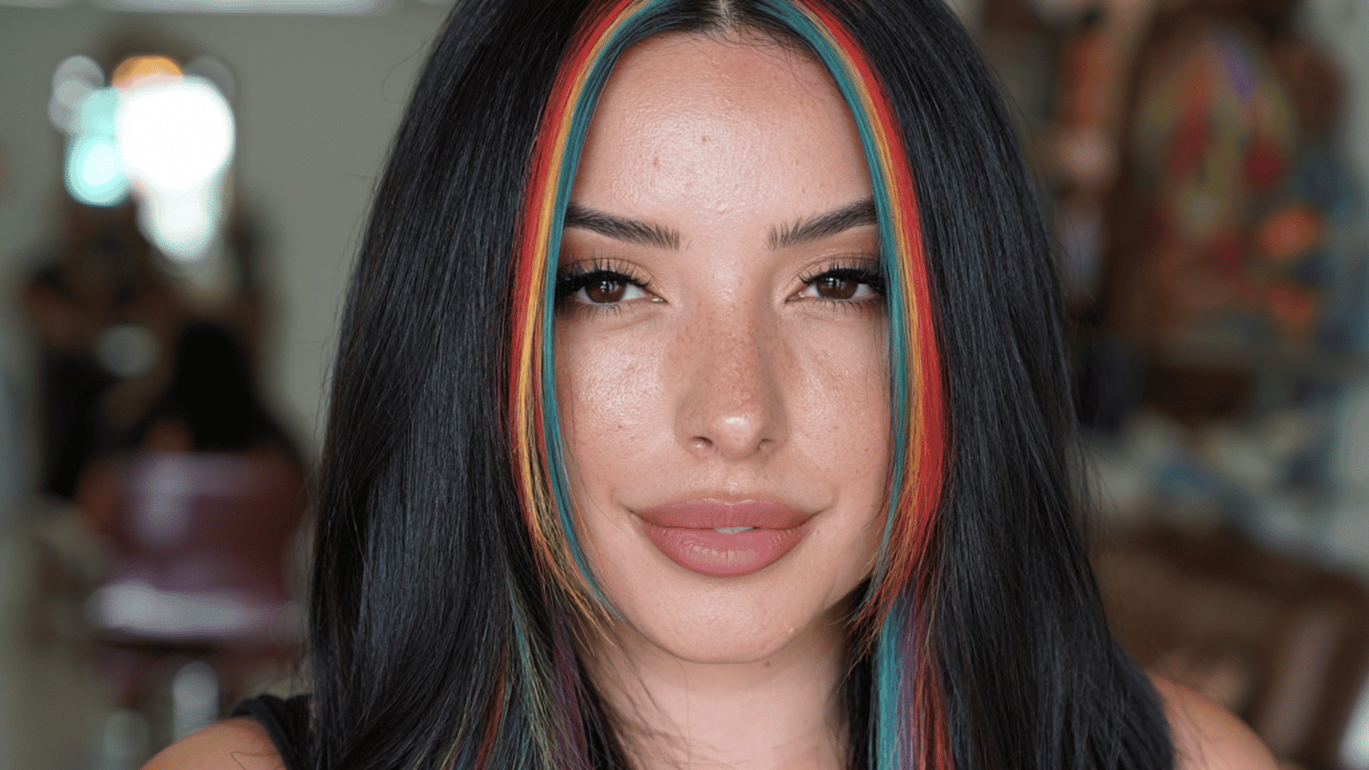 woman with vivid rainbow money piece strands framing long naturally styled black hair