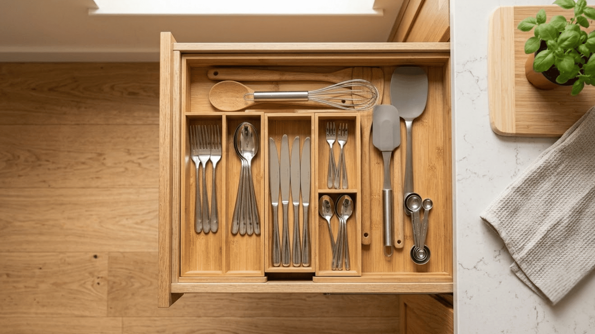 bamboo drawer organizer holding cutlery utensils and small kitchen tools in separate compartments