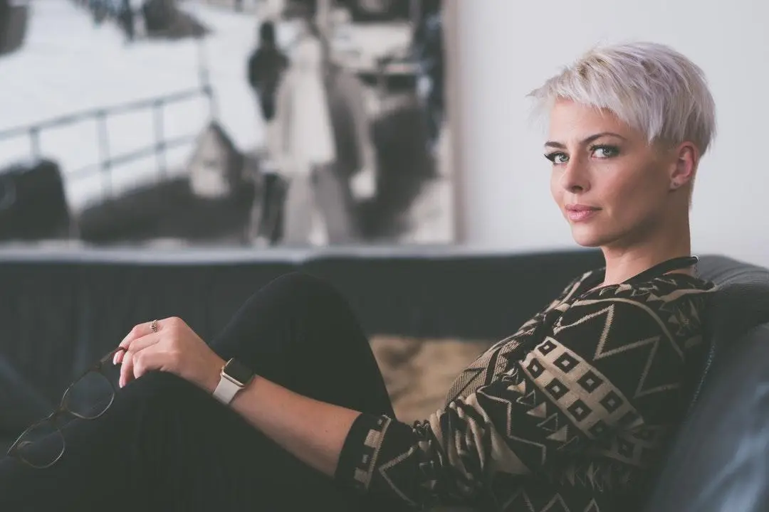 Short-haired woman reclining on sofa holding glasses in modern living room