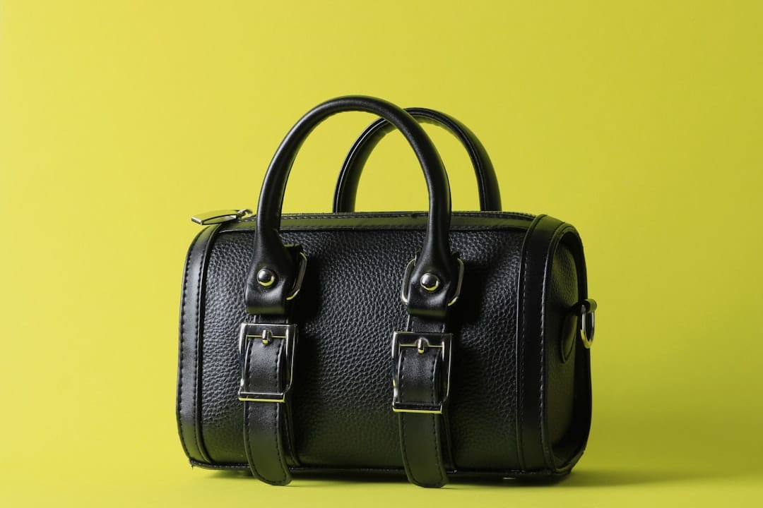 Black leather handbag with double straps on yellow background