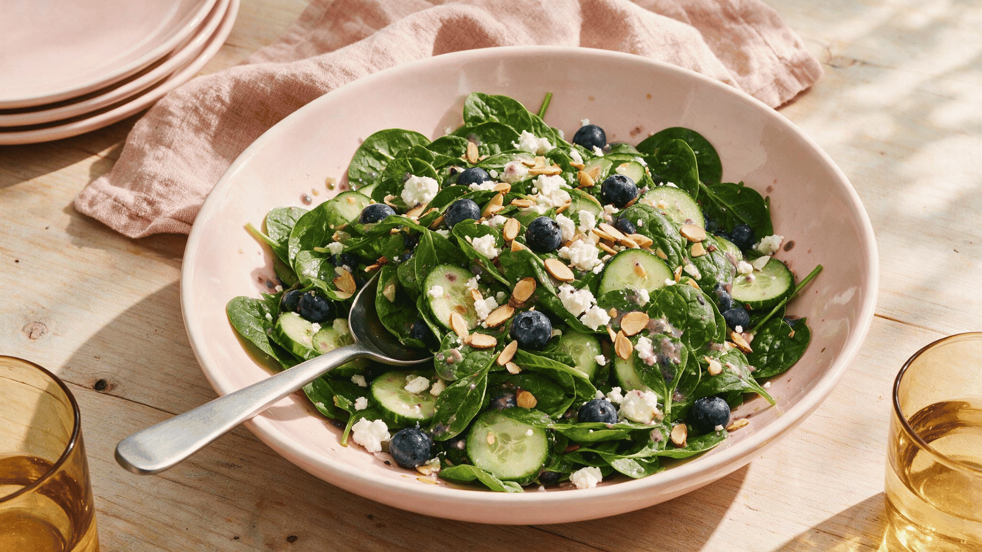 blueberry spinach salad with cucumber, feta, and toasted almonds in a pink bowl