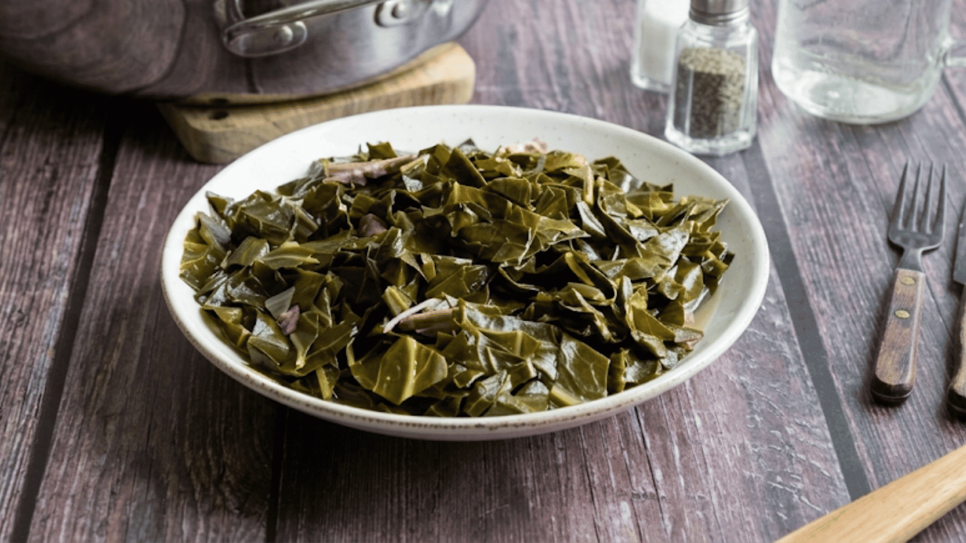 southern collard greens cooked until tender and served in a white bowl on a rustic wooden table