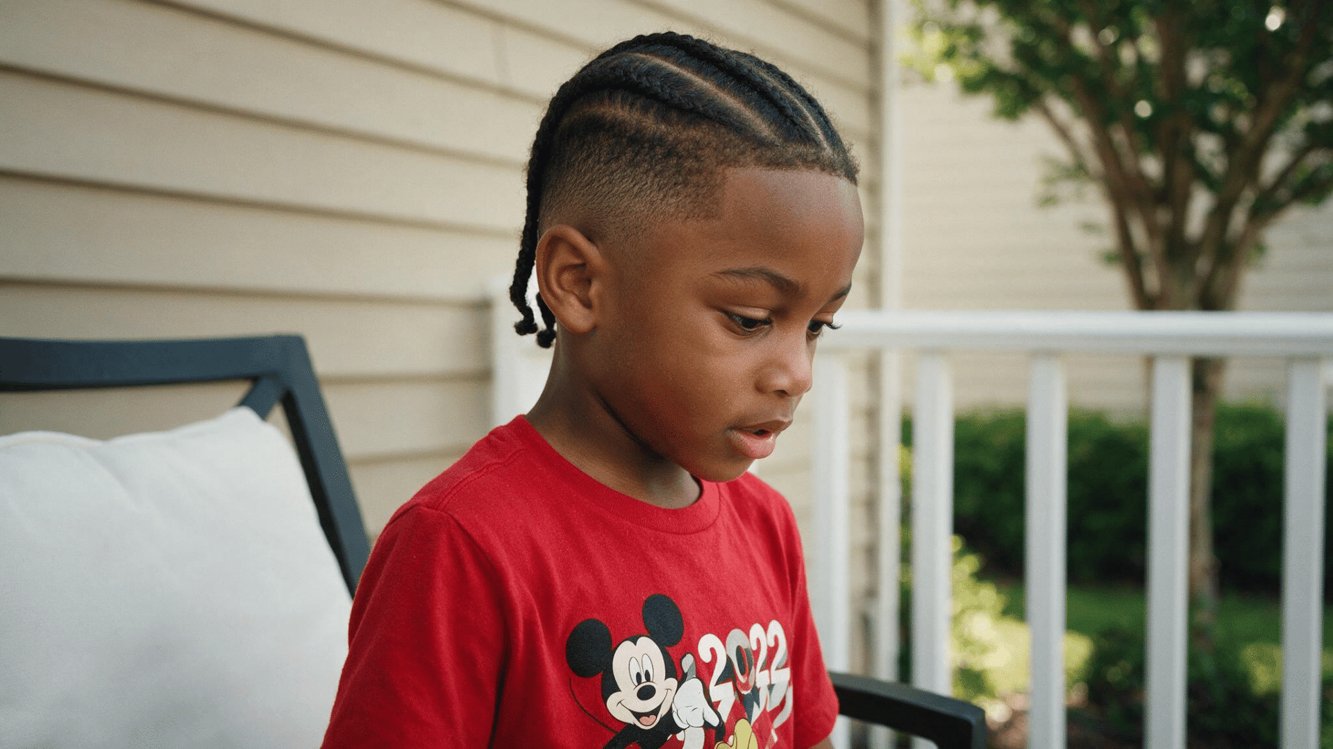 young boy wearing neat cornrows on top with closely faded sides and a clean hairline
