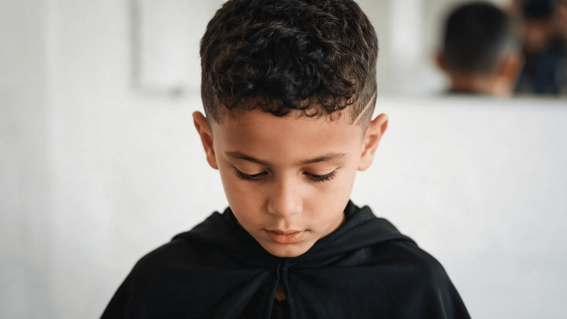 mixed boy haircut with short curls across the top, a forward fringe, and faded sides