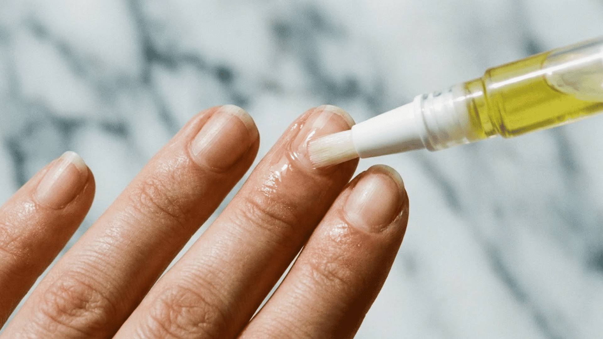 applying nourishing cuticle oil to natural fingernails with a brush pen applicator