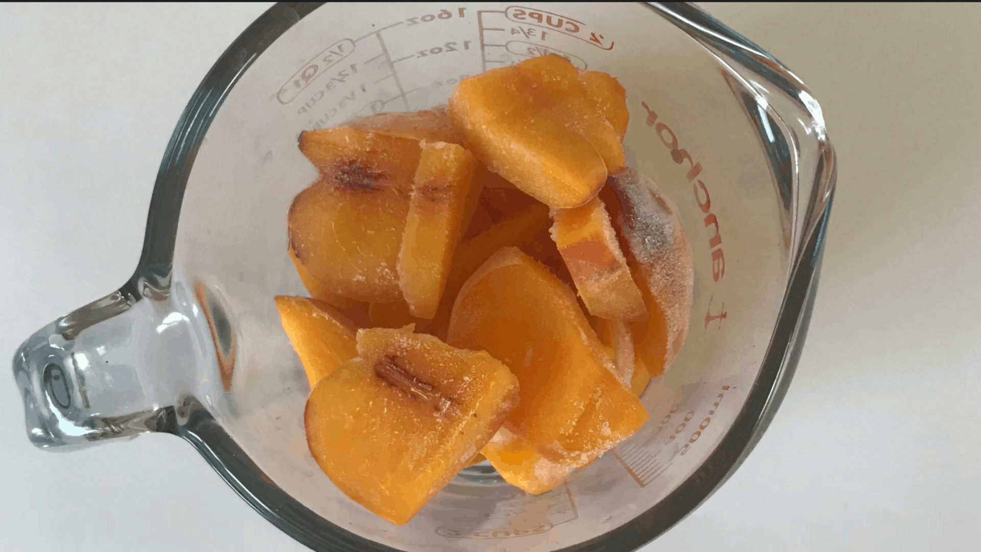 frozen peaches and banana added to a blender as the first step for making a creamy peach smoothie