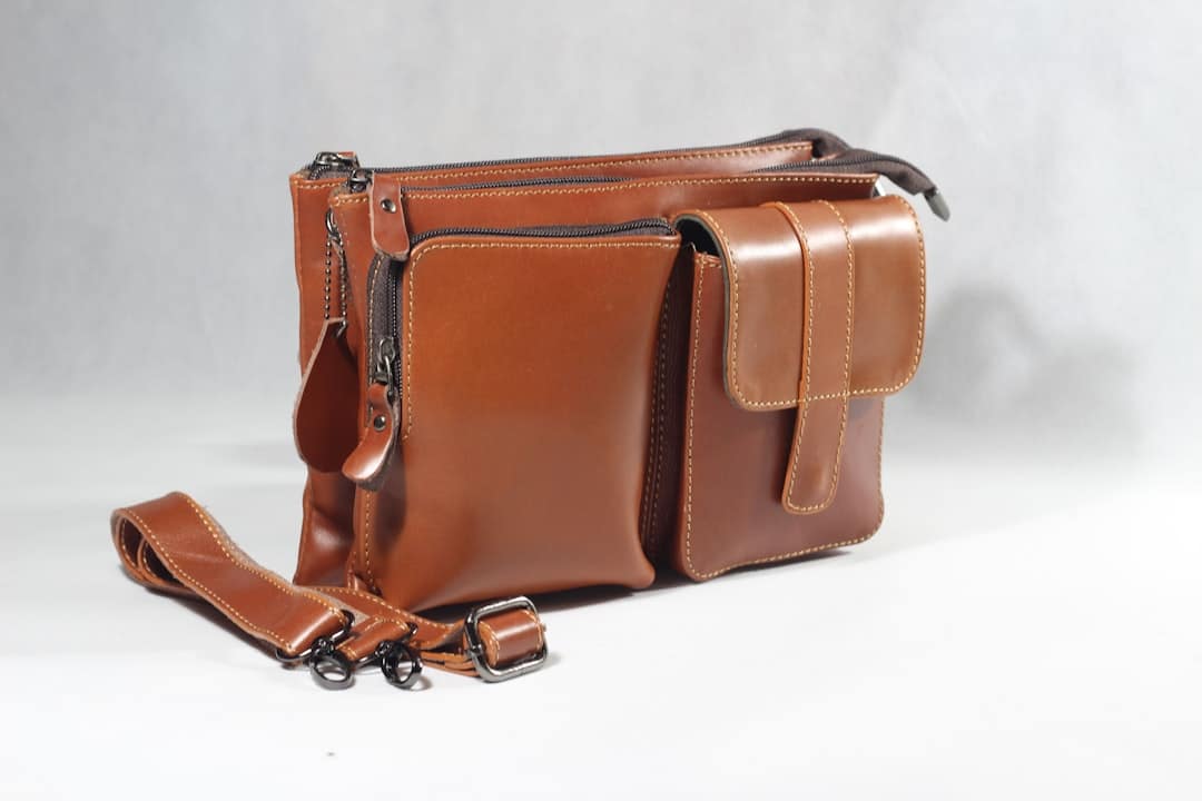 Brown leather crossbody bag with multiple compartments on light gray background