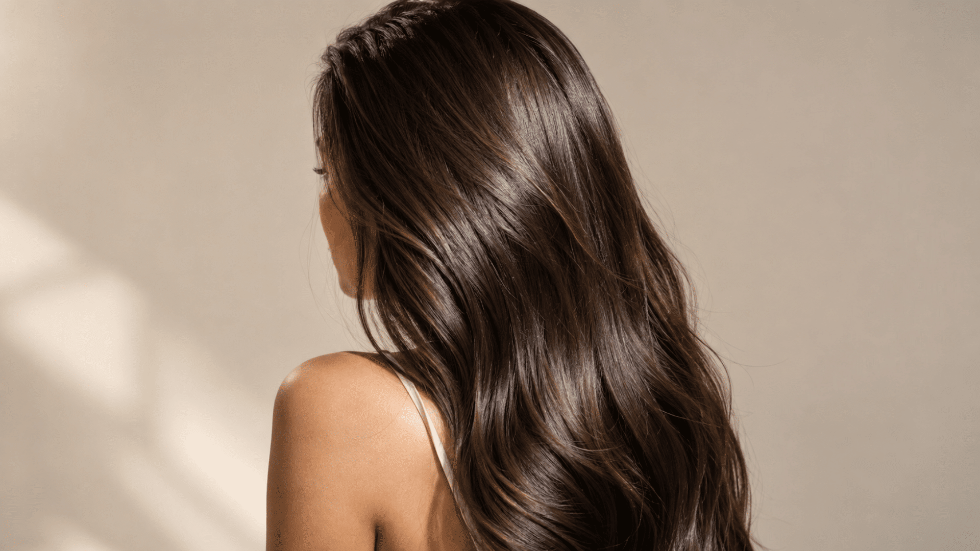 woman with long smooth glossy brown hair reflecting soft natural light