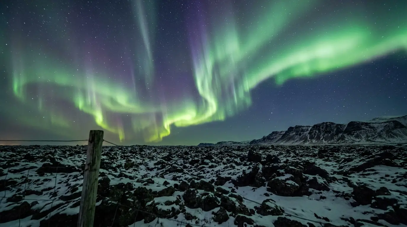 Northern lights illuminating snowy mountain landscape under starry night sky