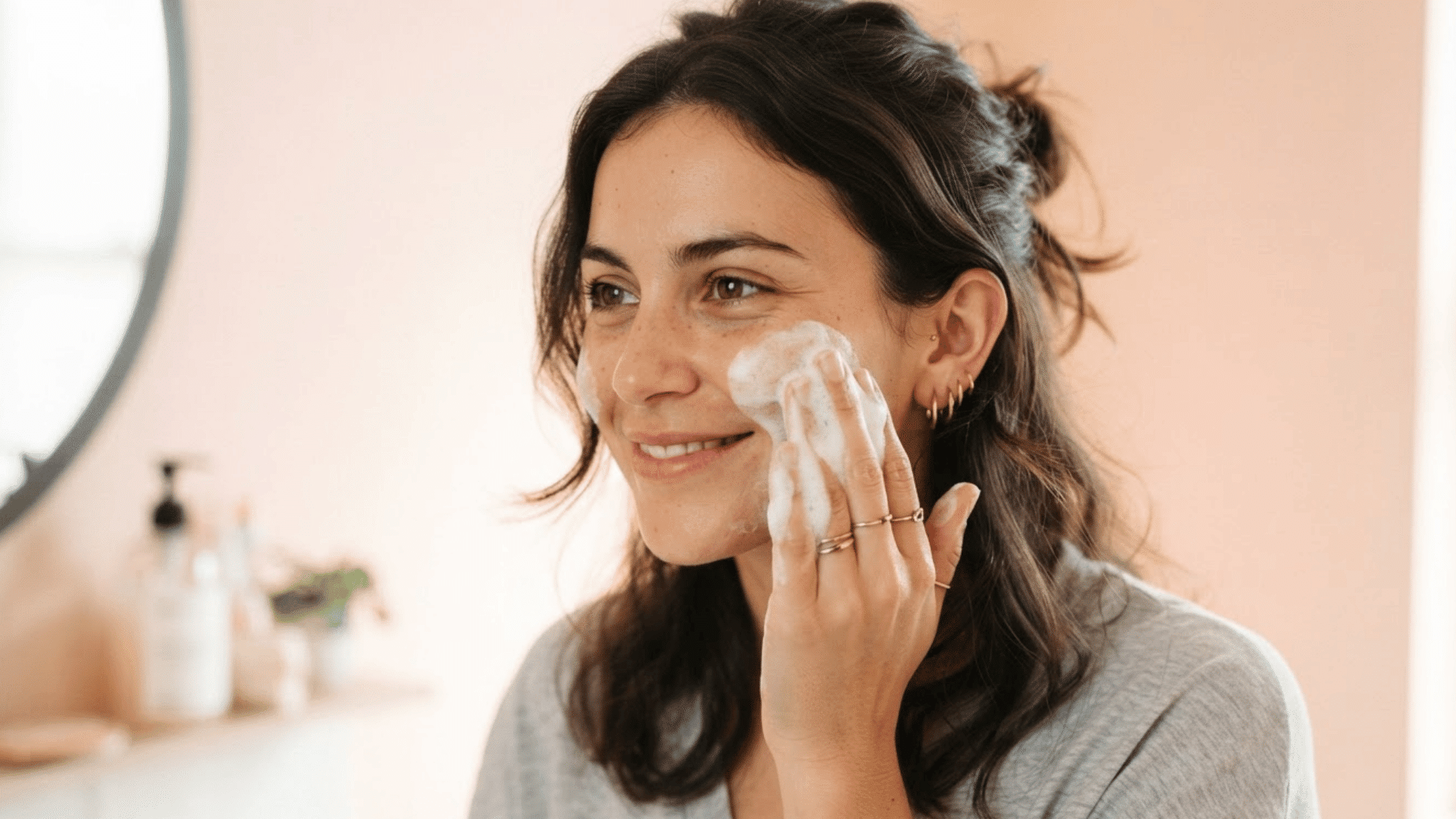 woman cleansing her face with a gentle cleanser as part of a simple daily skincare routine