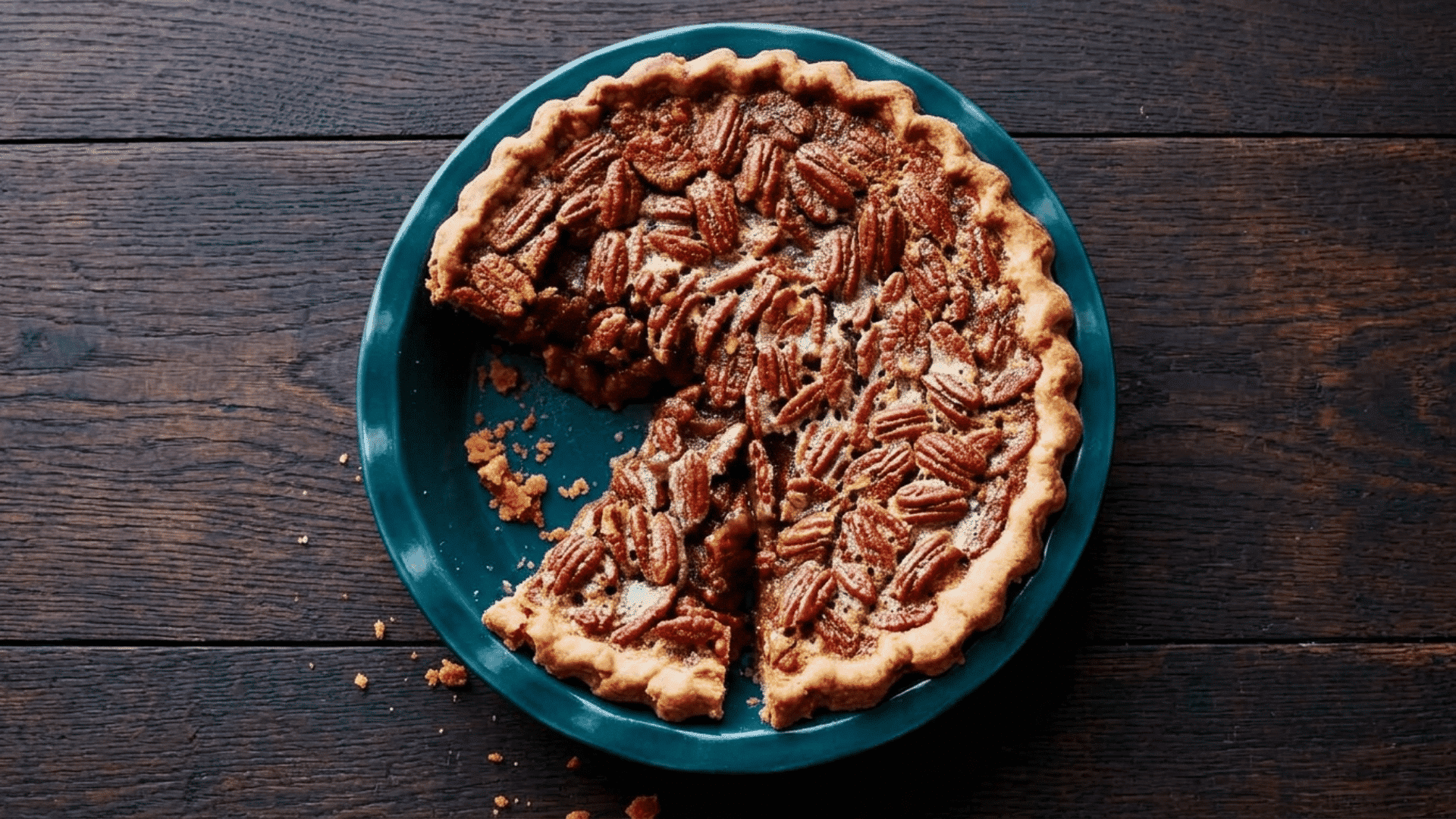 pecan pie with toasted pecans and flaky crust served on a blue plate over a rustic wooden table