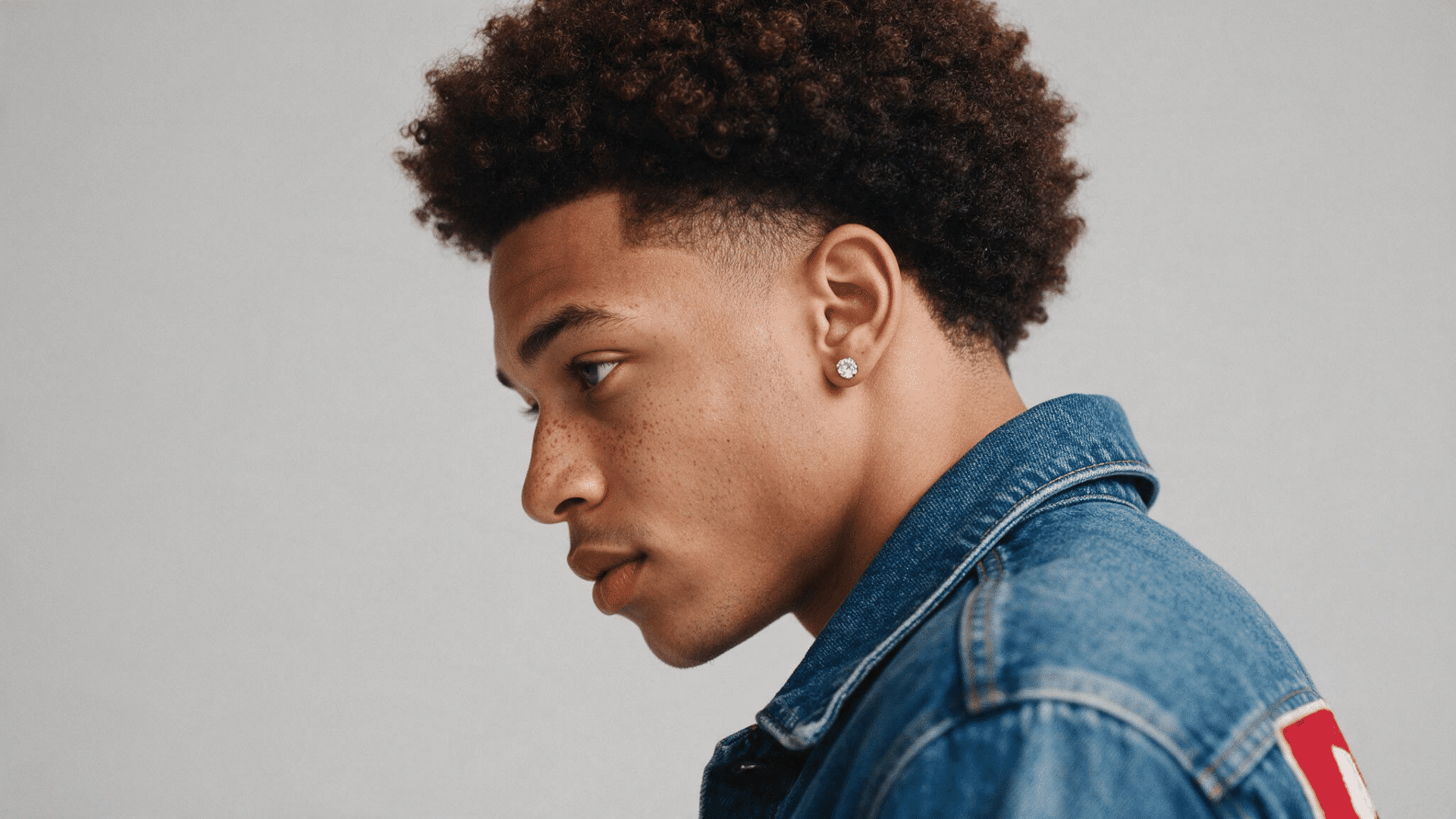 rounded afro taper haircut with full natural curls on top and neatly tapered sides around the ears