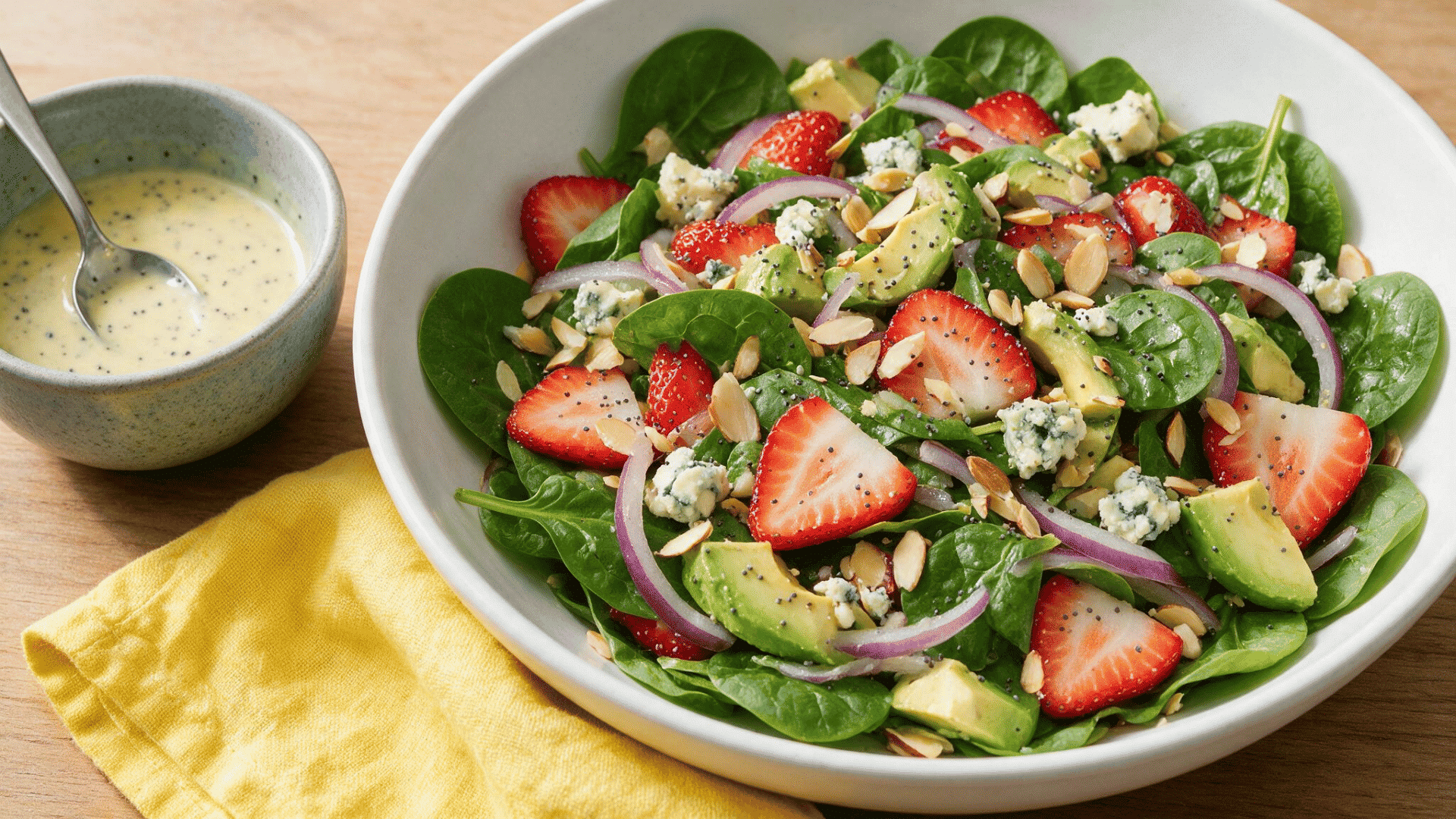 spinach salad with strawberries, avocado, red onion, blue cheese, almonds, and poppy seed dressing.