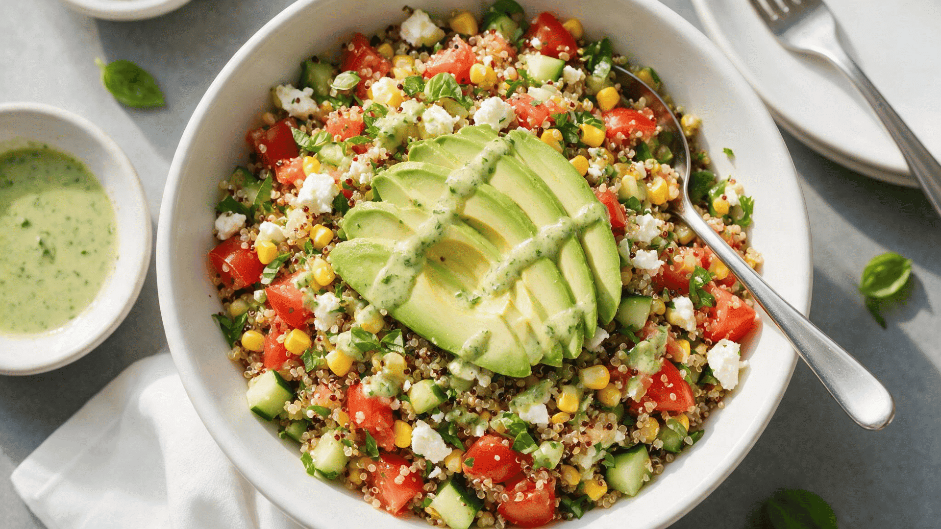 quinoa salad with tomatoes, corn, cucumber, feta, and fanned avocado with green dressing