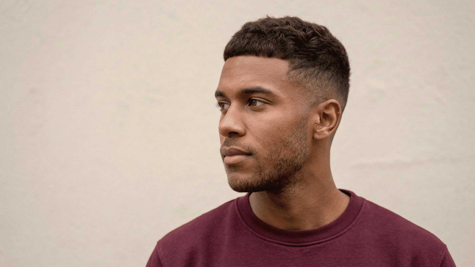 man with a textured crew cut featuring a short choppy top and smoothly faded sides against a neutral background